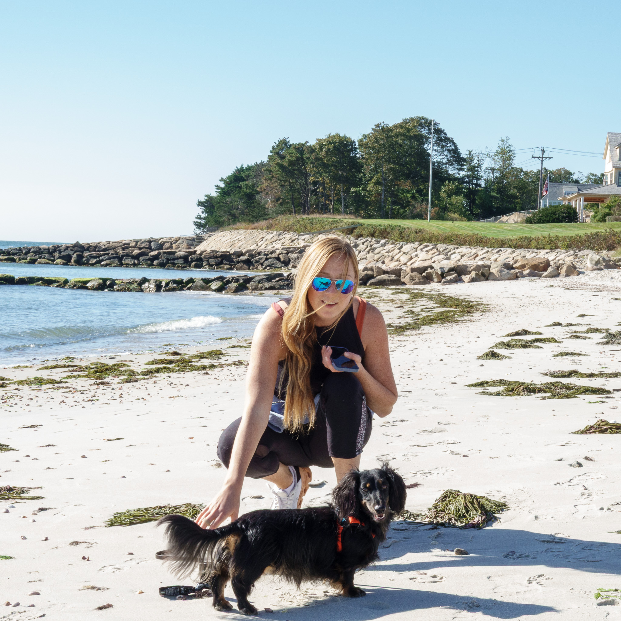 Lane crouched on a Cape Cod beach with Wally, her long-haired dachshund.